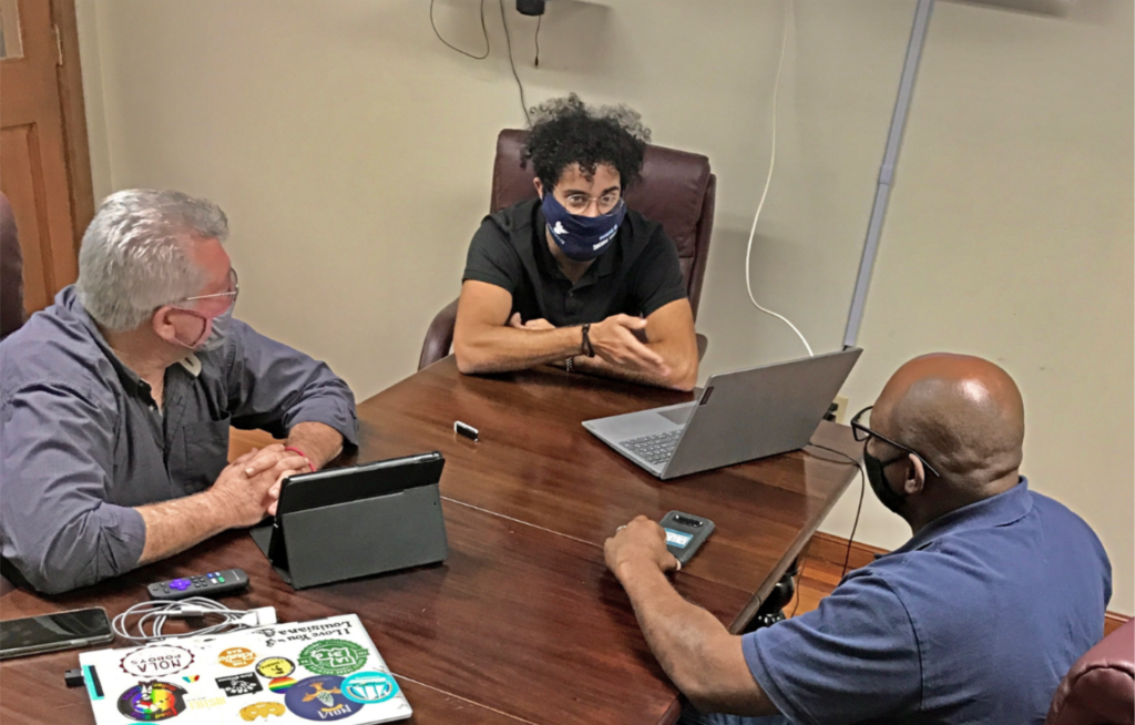 Volunteer Rafael training staff members Steve Amort and Louis Gibson on his database