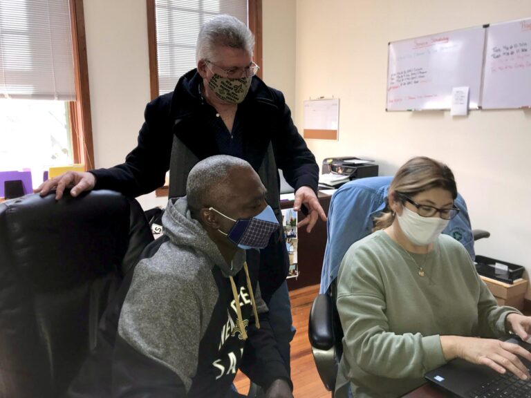 Reentry Manager Steve Amort and Reentry Specialist Christi Cheramie assisting client Paul on the computer