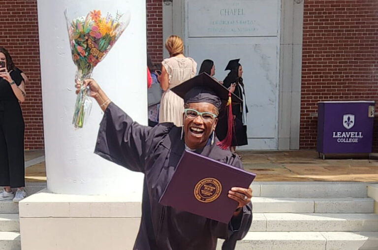 Parole Project Client Demetricy Moore holding her diploma and a bouquet of flowers as she celebrates her graduation from Leavell College